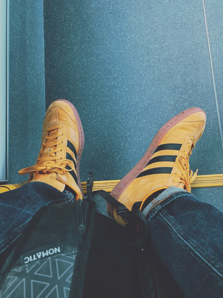 Blick auf meine gelben Turnschuhe und meinen Rucksack unterwegs.